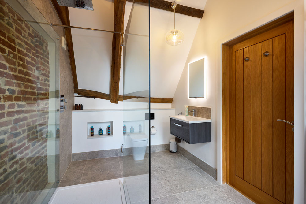 a luxury bathroom in a historic building with treated beams overhead